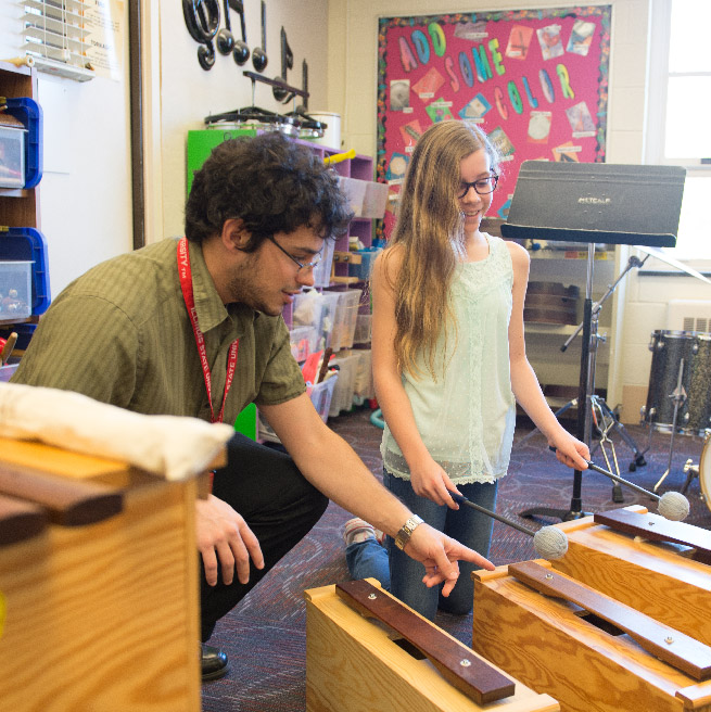 Student teacher playing drums with a little girl. 