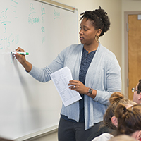 Woman writes on white board. 