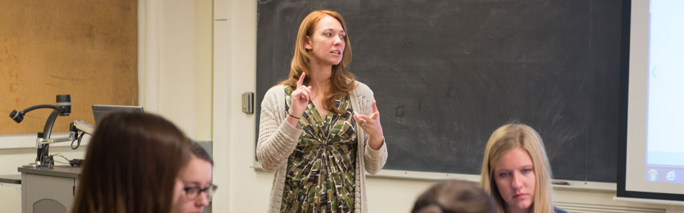 Professor instructs students working on their computers.